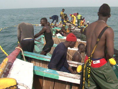 Die Fischer auf der Pirogue machen sich an den großen Schließnetzen zu schaffen