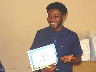 Alah Emmanuel Akomaye sonríe al recibir su diploma y premio